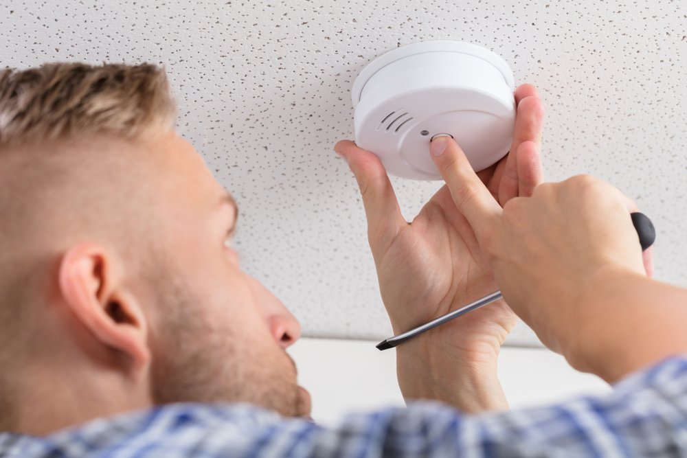 A professional from Steamatic tests a replacement smoke detector f=in a client's home